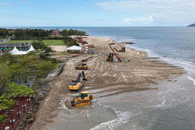 Conter o mar ou recuar? O futuro das cidades costeiras Máquinas e tubulações realizando obra de engordamento da faixa de areia