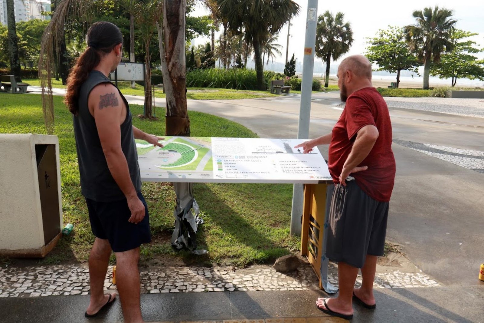 Quebra-Mar recebe mapas táteis; rota ainda será concluída Duas pessoas consultam um mapa tátil no Novo Quebra-Mar, em Santos.